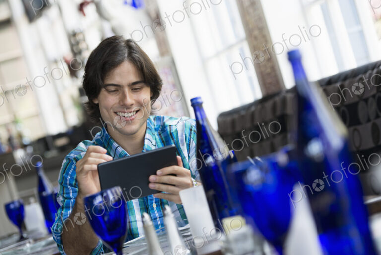 A cafe interior. A man sitting using a digital tablet.