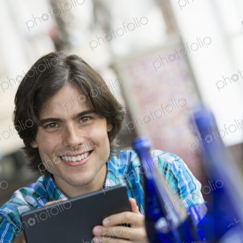 A cafe interior. A man sitting using a digital tablet.