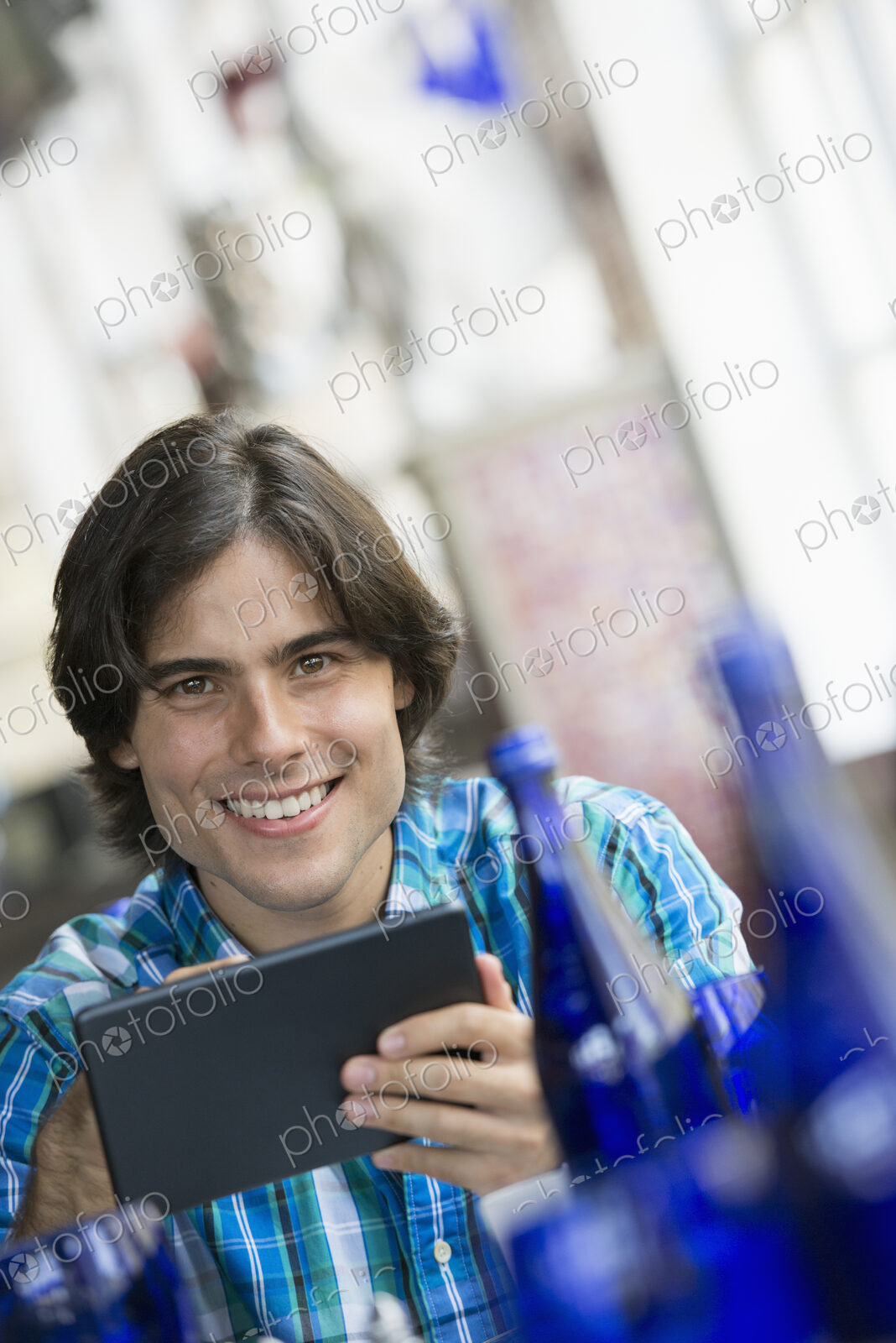 A cafe interior. A man sitting using a digital tablet.