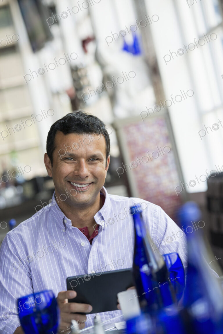 A cafe interior. A man sitting using a digital tablet.