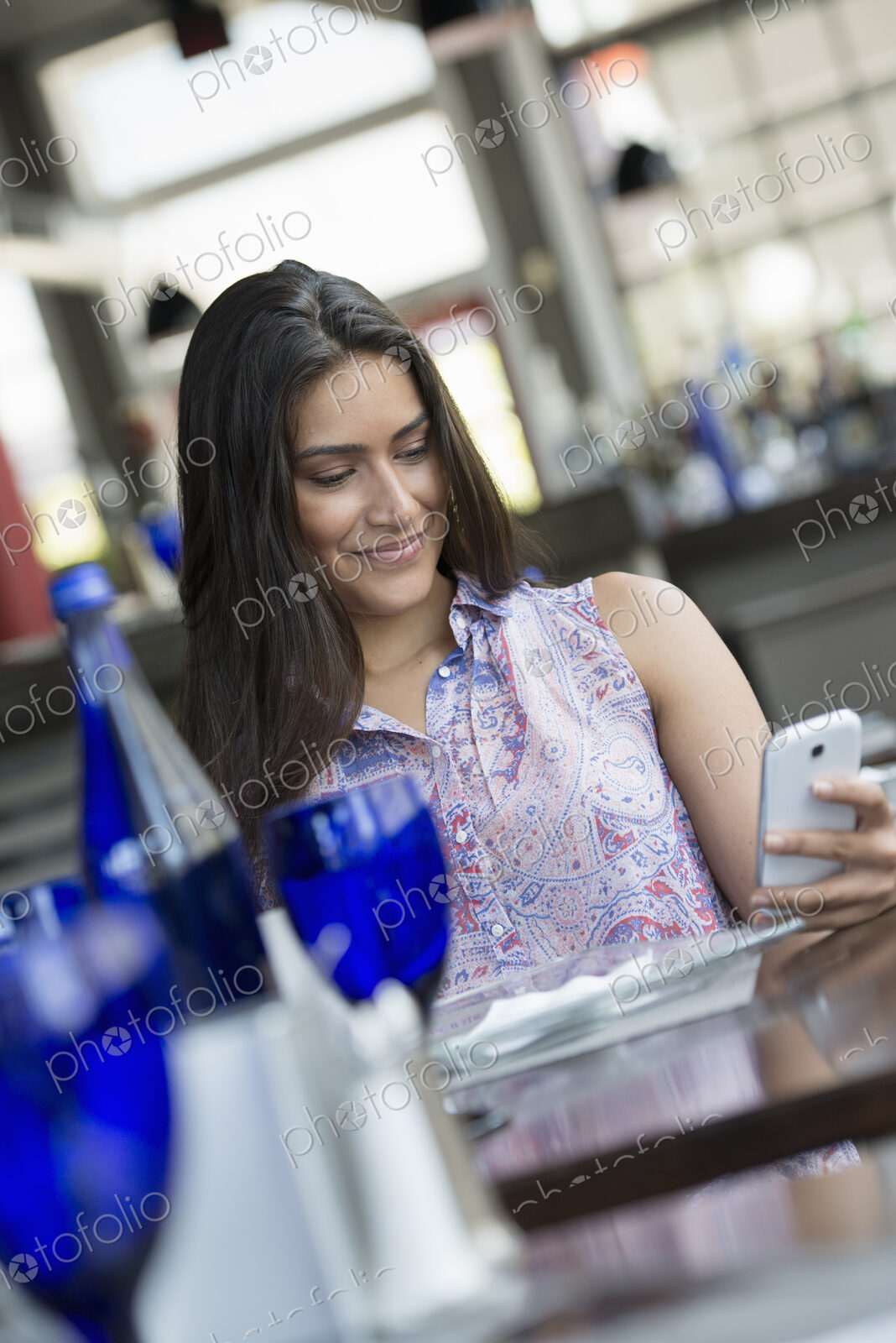 A cafe interior. A woman using a smart phone.