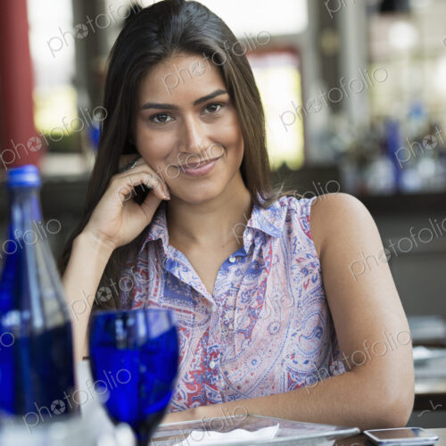 A cafe interior. A young woman relaxing at a table.