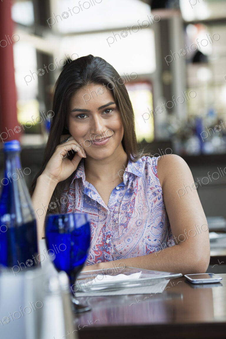 A cafe interior. A young woman relaxing at a table.