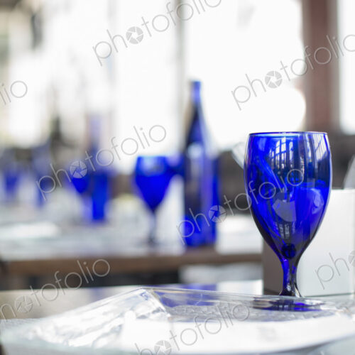 A cafe interior. Bright blue glassware on empty tables. A cafe interior. Bright blue glassware on empty tables.