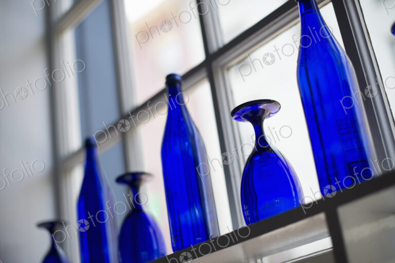 A cafe interior. Bright blue glassware on empty tables.