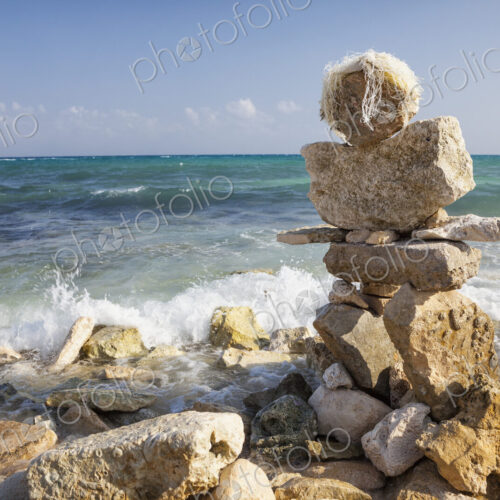 A cairn, pile of stones on the beach at the water's edge A cairn, pile of stones on the beach at the water's edge