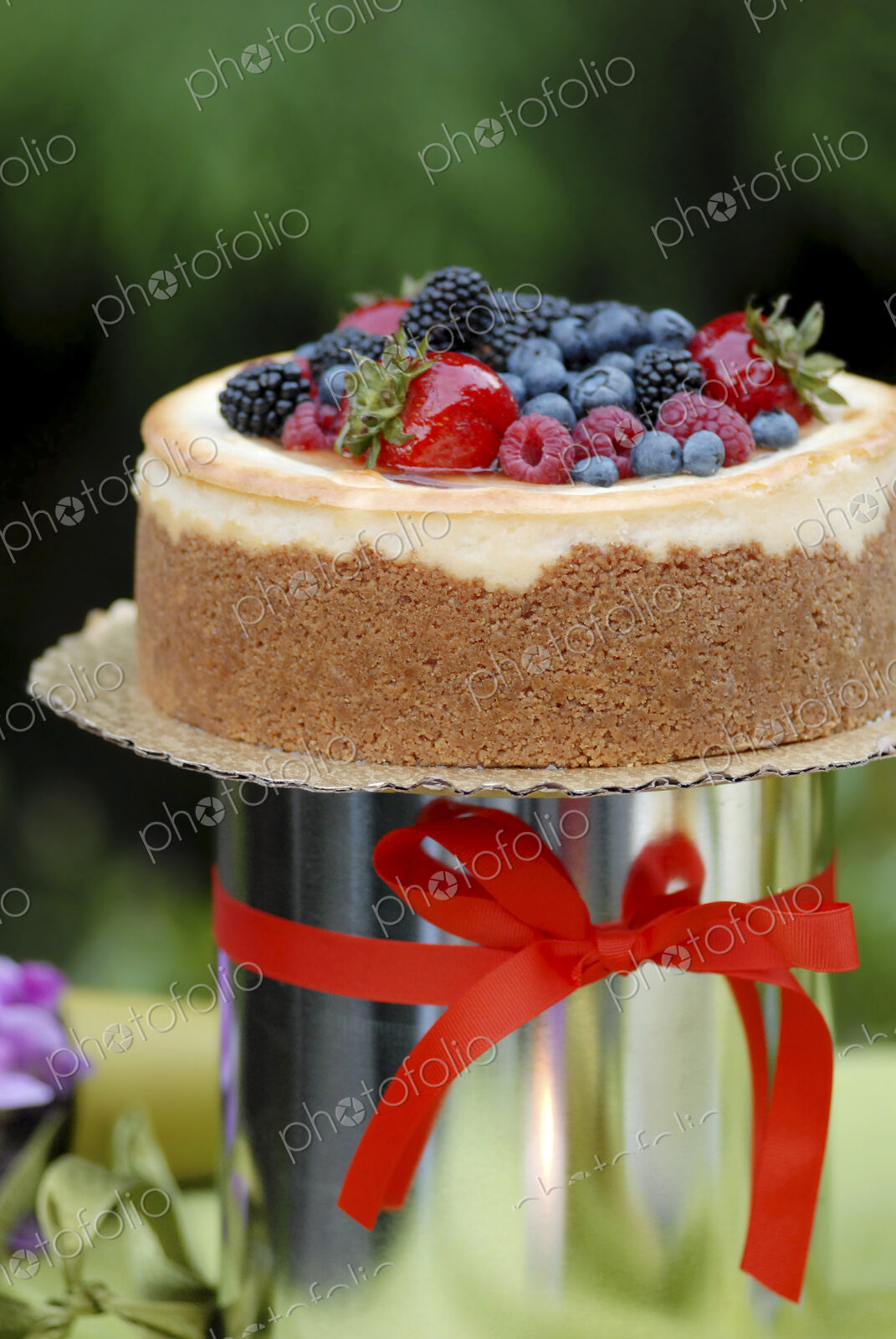 A cake with icing and fresh berries and a red ribbon.