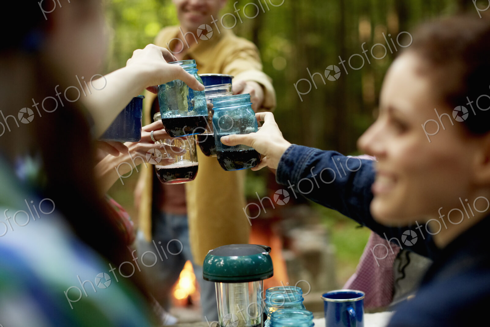 A campsite clearing in the woods. People seated around a table.