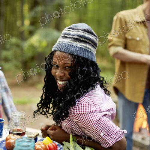 A campsite clearing in the woods. People seated around a table.