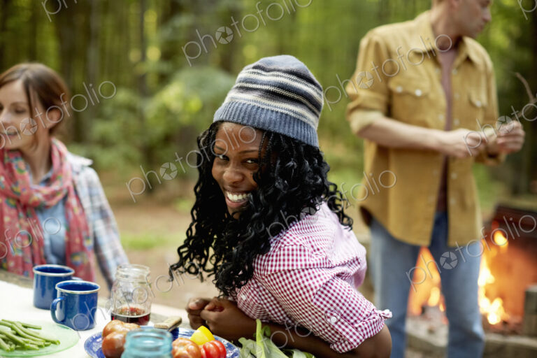 A campsite clearing in the woods. People seated around a table.