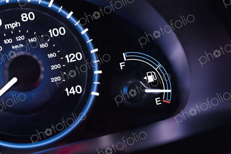 A car interior, the dashboard,instrument panel,and fuel gauge. A speedometer.