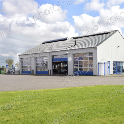 A car workshop or garage with doors open and cars on the forecourt. A car workshop or garage with doors open and cars on the forecourt.