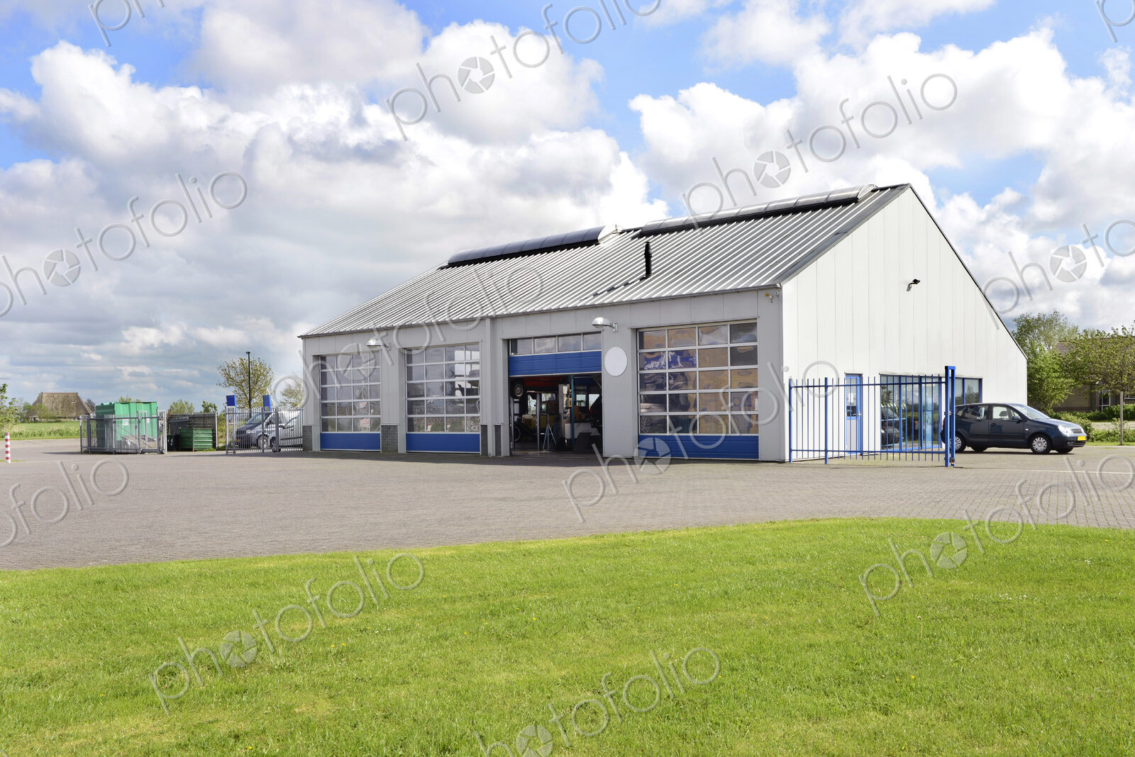 A car workshop or garage with doors open and cars on the forecourt.
