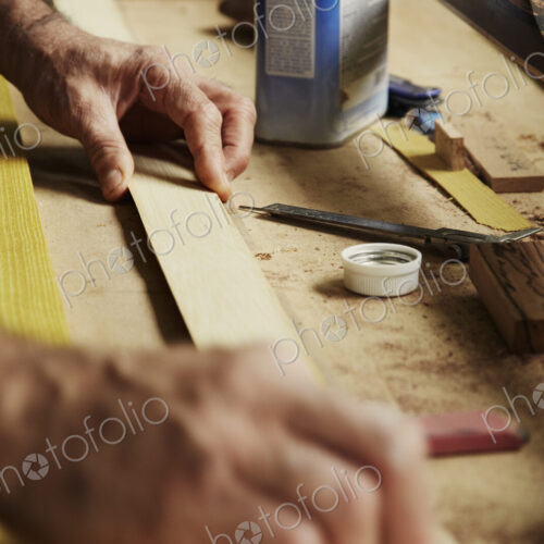 A carpenter at a workbench holding a piece of wood. A carpenter at a workbench holding a piece of wood.