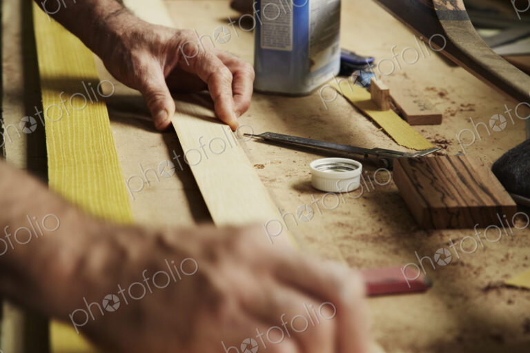 A carpenter at a workbench holding a piece of wood.