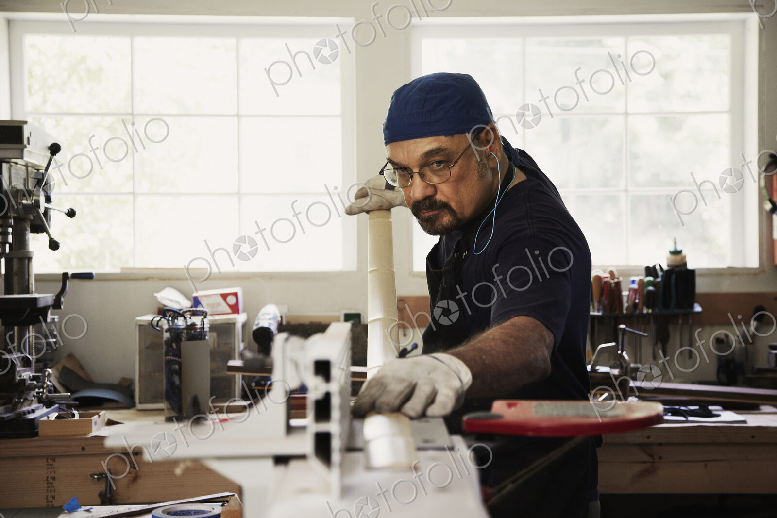 A carpenter, bow maker, sanding a long piece of wood for a bow in his workshop.