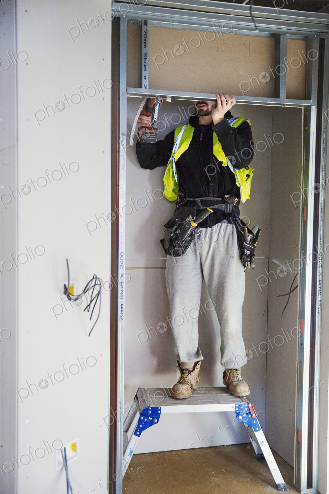 A carpenter in a small space fitting a shelf into a wall cupboard.