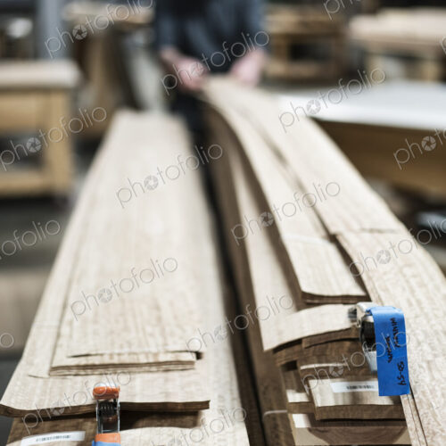 A carpenter in a woodworking shop gathering pieces of wood veneer. A carpenter in a woodworking shop gathering pieces of wood veneer.