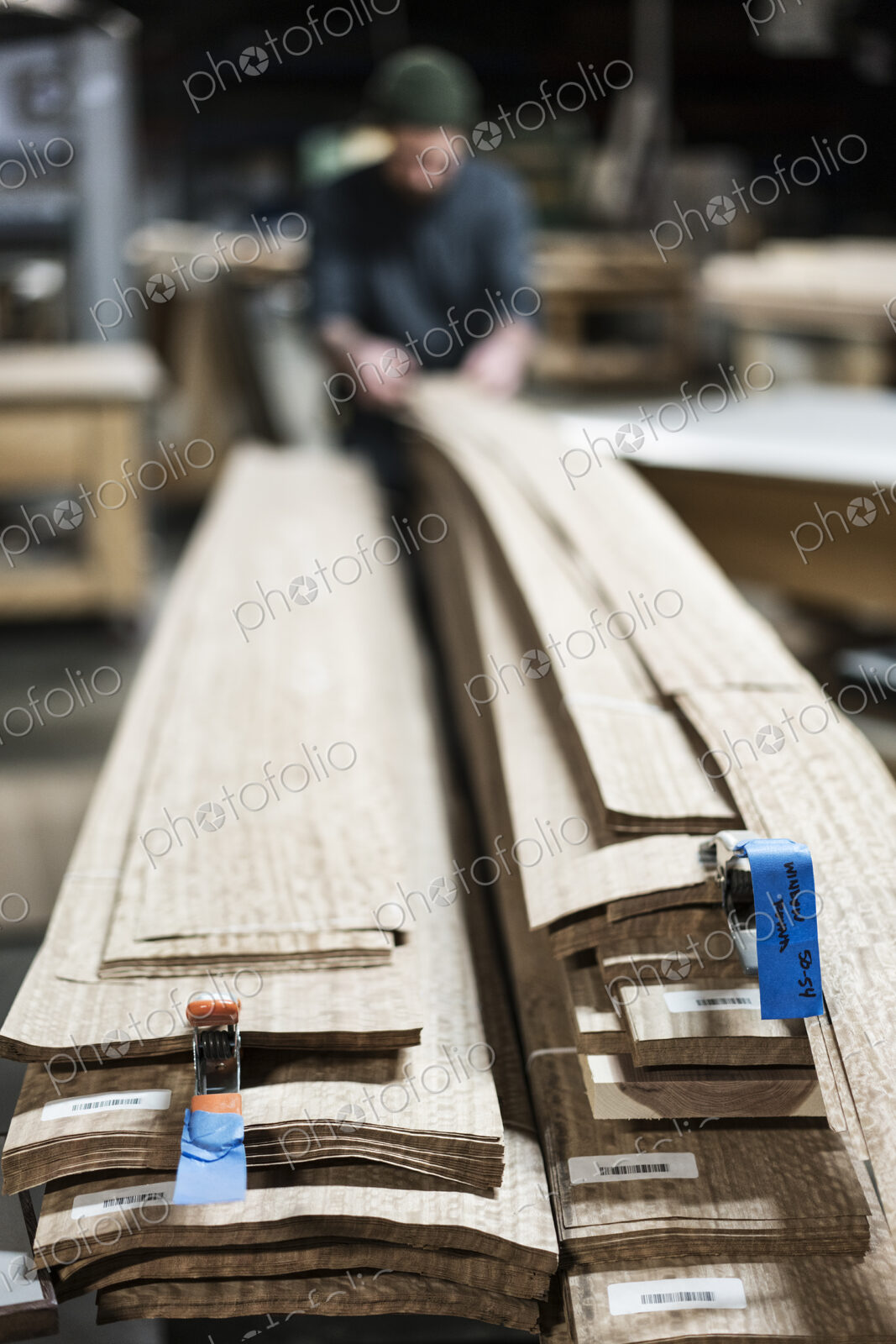 A carpenter in a woodworking shop gathering pieces of wood veneer.