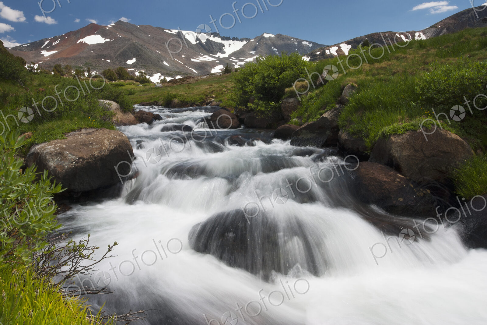 A cascade of fast flowing white water over rocks in a valley in the mountains.