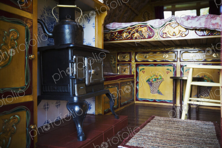 A cast iron stove with large metal kettle, a mantlepiece and storage cupboards and…