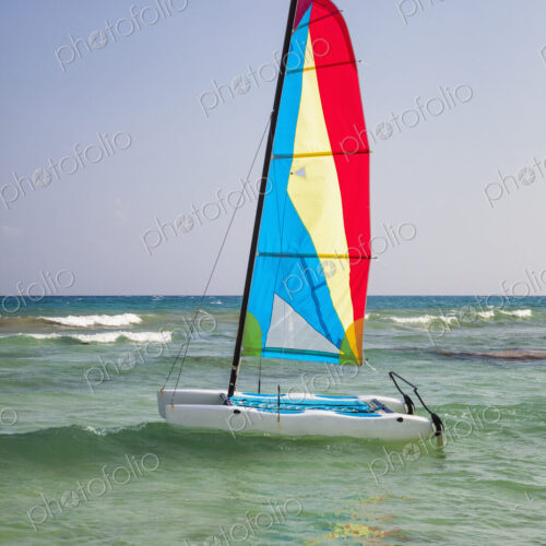 A catamaran in shallow water with the sail up. A catamaran in shallow water with the sail up.