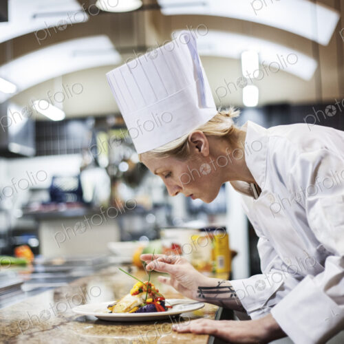 A caucaisan female chef putting the finishing touches on a plate of fish in a…