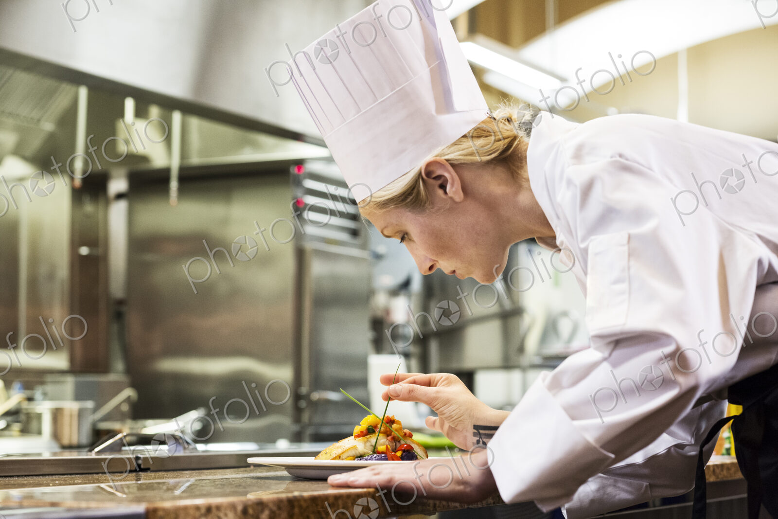 A caucaisan female chef putting the finishing touches on a plate of fish in a…