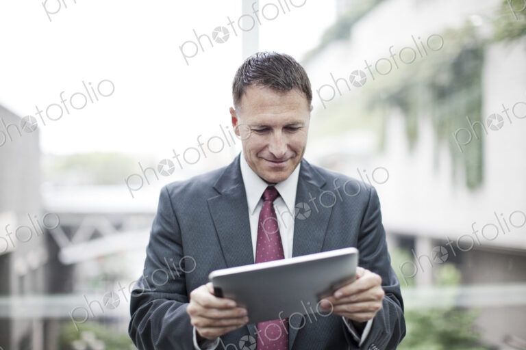 A caucasian businessman checking his notebook computer while standing in a convention…