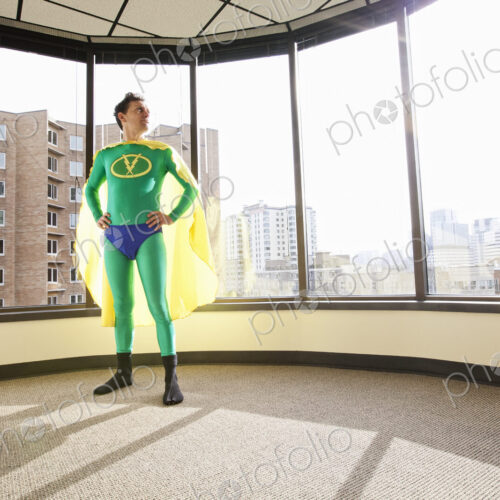 A caucasian businessman office super hero stands at an office window and ponders his… A caucasian businessman office super hero stands at an office window and ponders his…