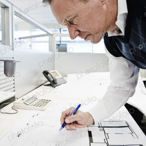 A caucasian businessman working on plans for an office layout.