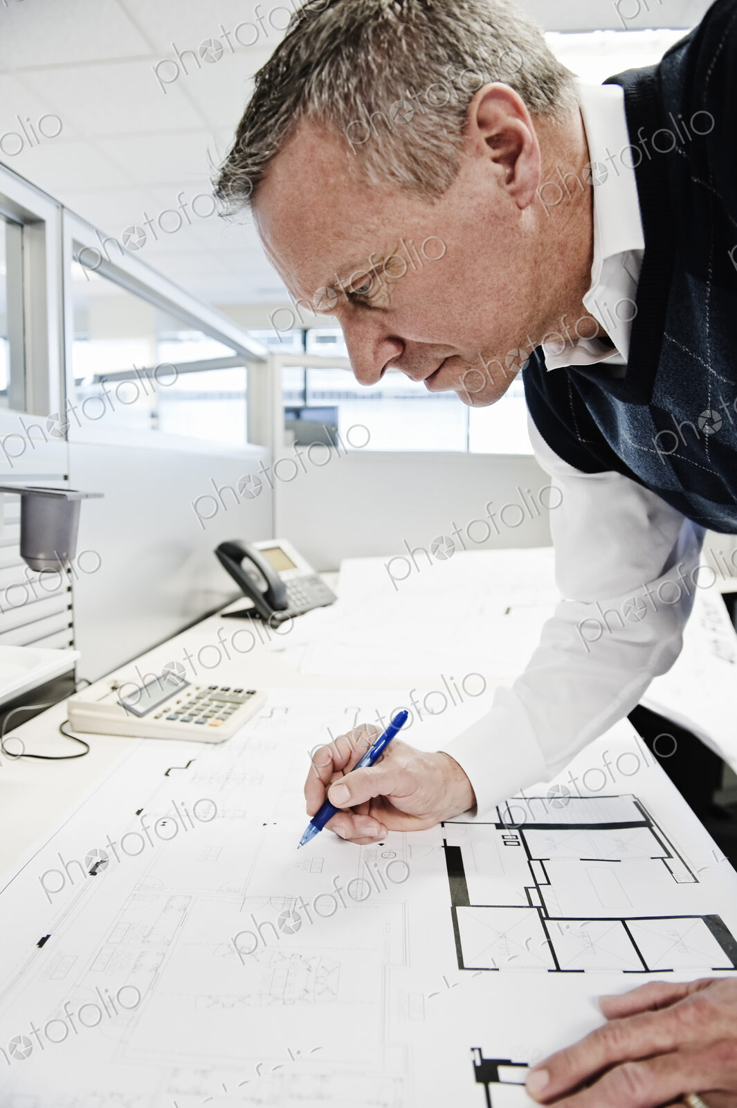 A caucasian businessman working on plans for an office layout.