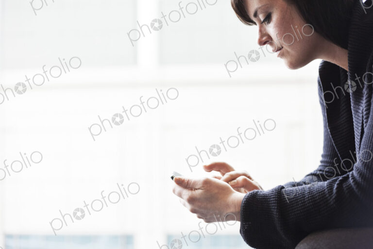 A caucasian businesswoman working on a cell phone.