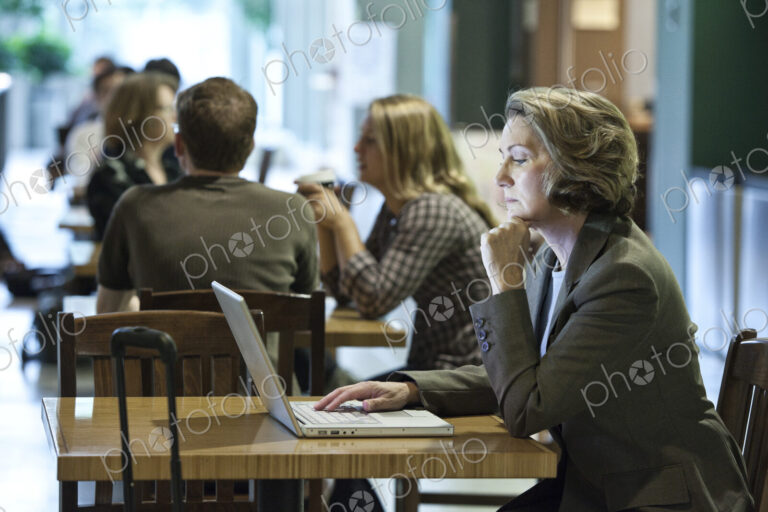 A caucasian businesswoman working on a laptop computer while sitting in a cafe.