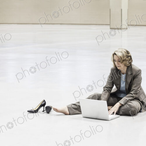 A caucasian businesswoman working on a laptop on the floor of a convention center