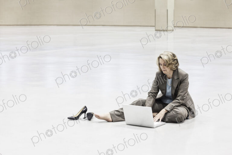 A caucasian businesswoman working on a laptop on the floor of a convention center