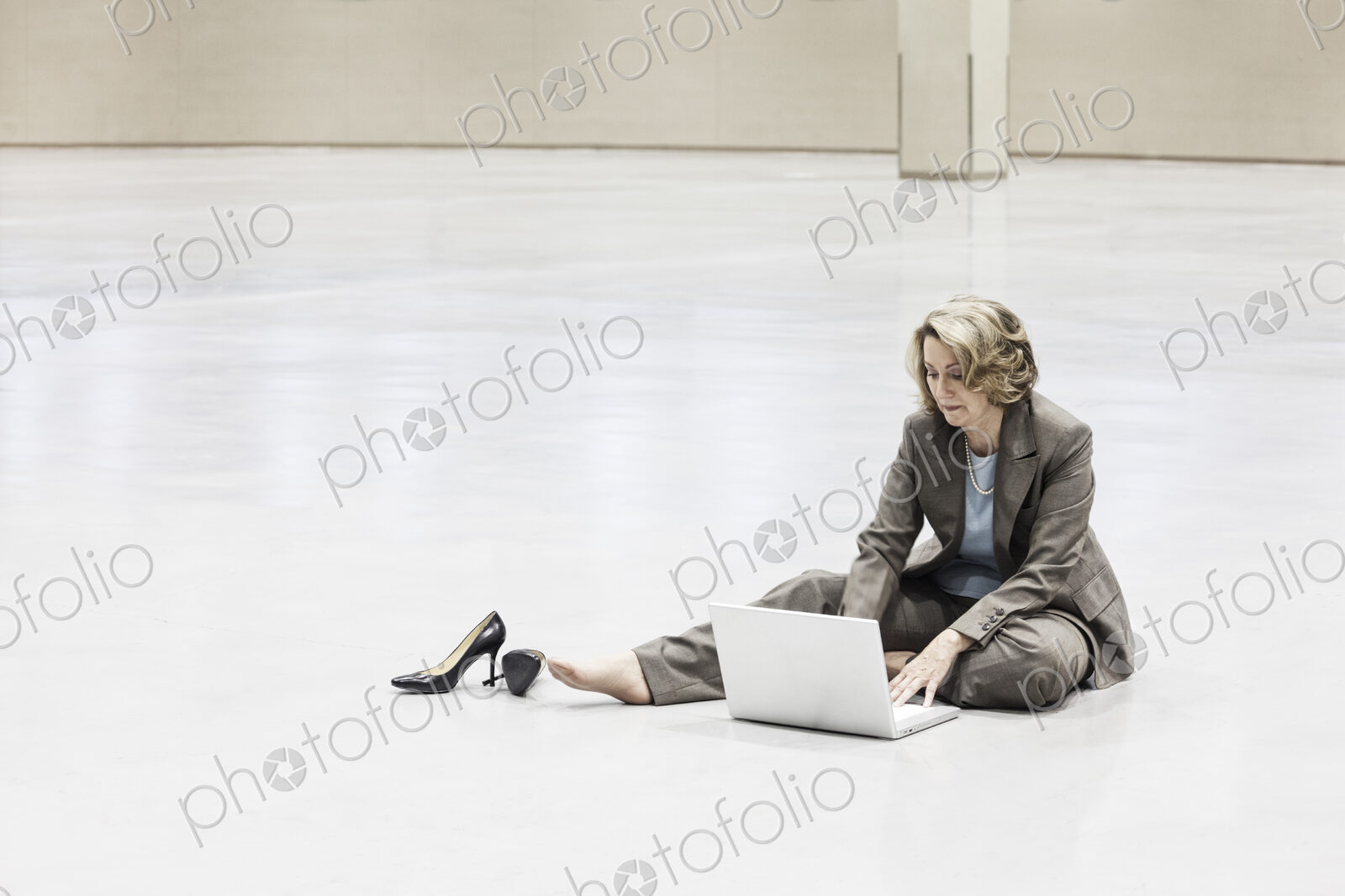 A caucasian businesswoman working on a laptop on the floor of a convention center