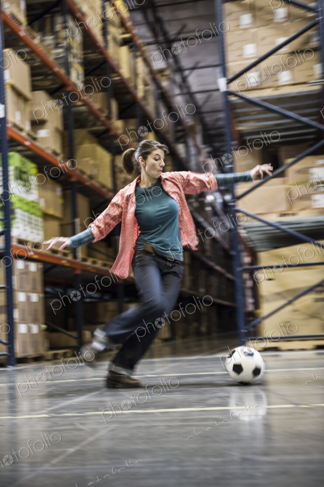 A caucasian female aboiut to kick a soccer ball during a work break in a distribution…