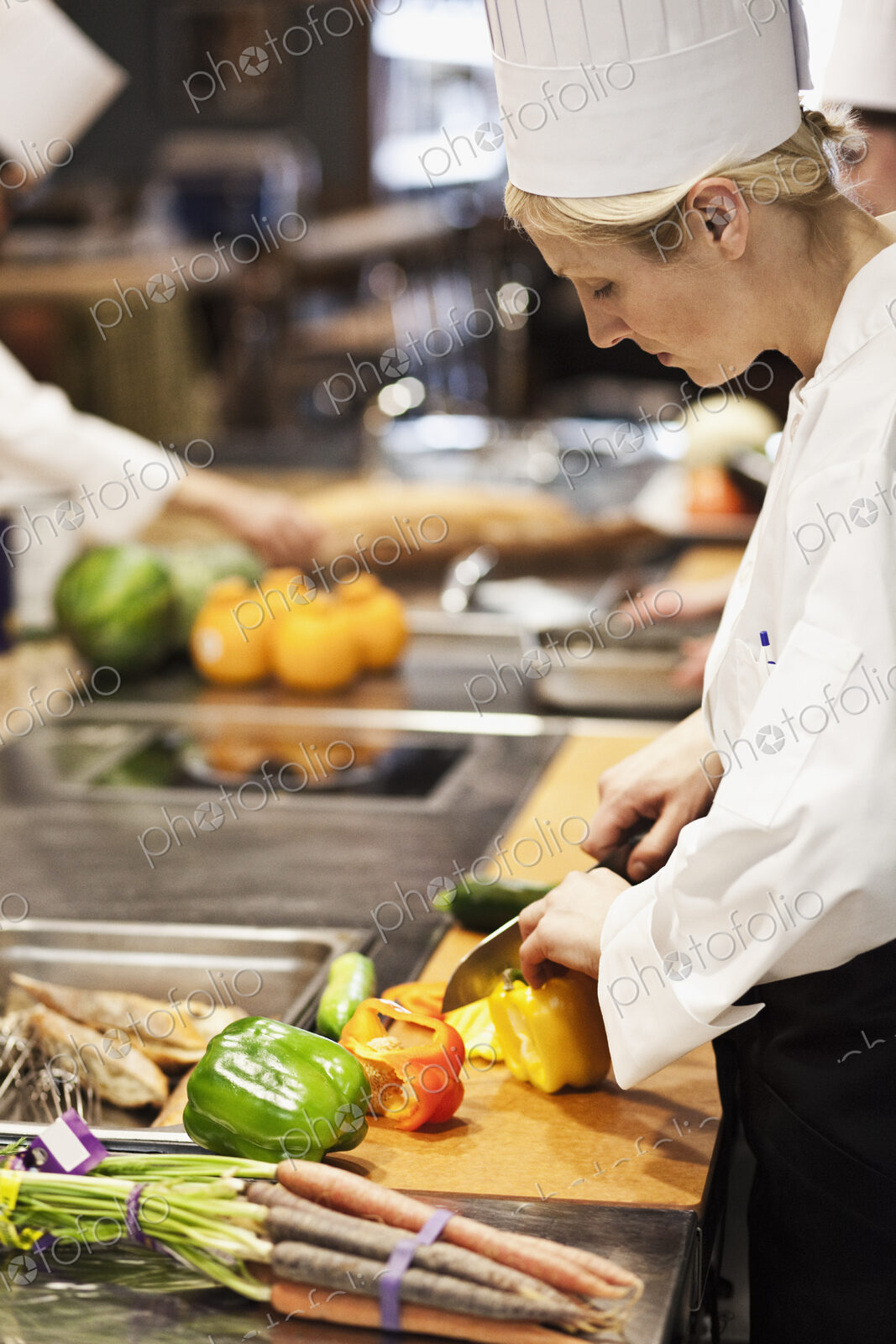 A caucasian female chef works cutting vegetables in a commercial kitchen,