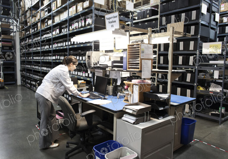 A caucasian female technician checking for parts on a desktop computer in a storage…