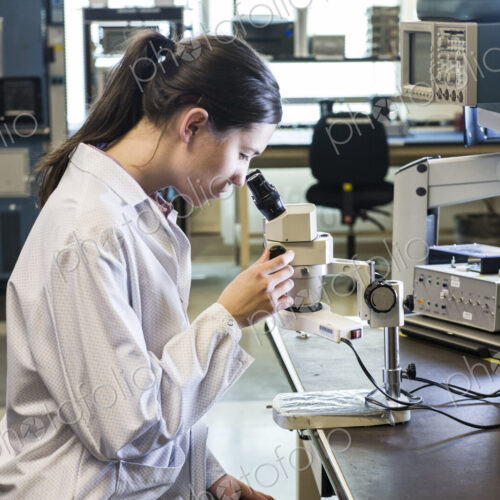 A caucasian female technician using a microscope in research and development