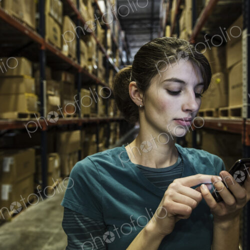 A caucasian female worker checking her phone for texts in warehouse A caucasian female worker checking her phone for texts in warehouse