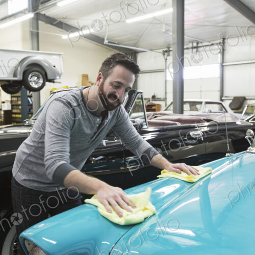 A caucasian male car mechanic applying wax to the hood of an old sedan in his classic… A caucasian male car mechanic applying wax to the hood of an old sedan in his classic…