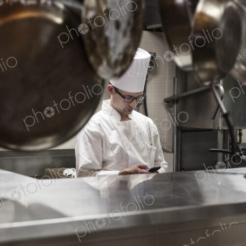A caucasian male chef checking his cell phone in a commercial kitchen, A caucasian male chef checking his cell phone in a commercial kitchen,