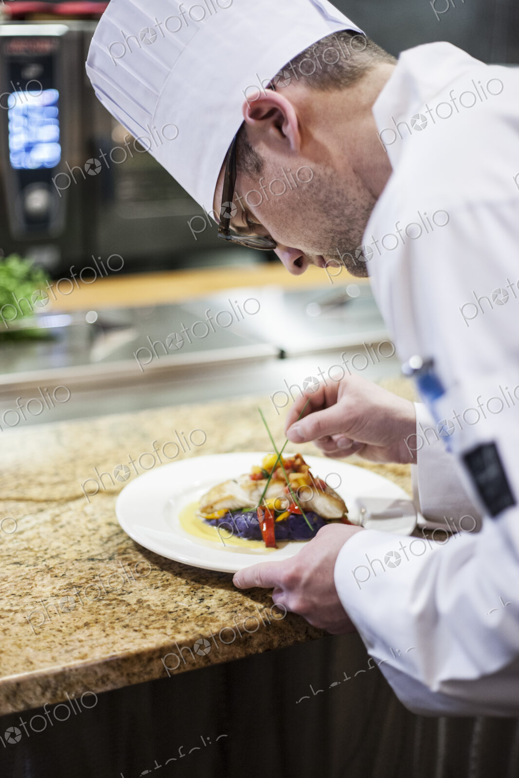 A caucasian male chef putting the finishing touches on a plate of fish in a commercial…