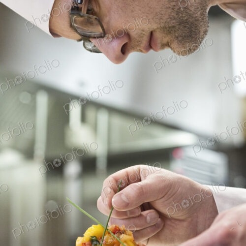 A caucasian male chef putting the finishing touches on a plate of fish in a commercial… A caucasian male chef putting the finishing touches on a plate of fish in a commercial…