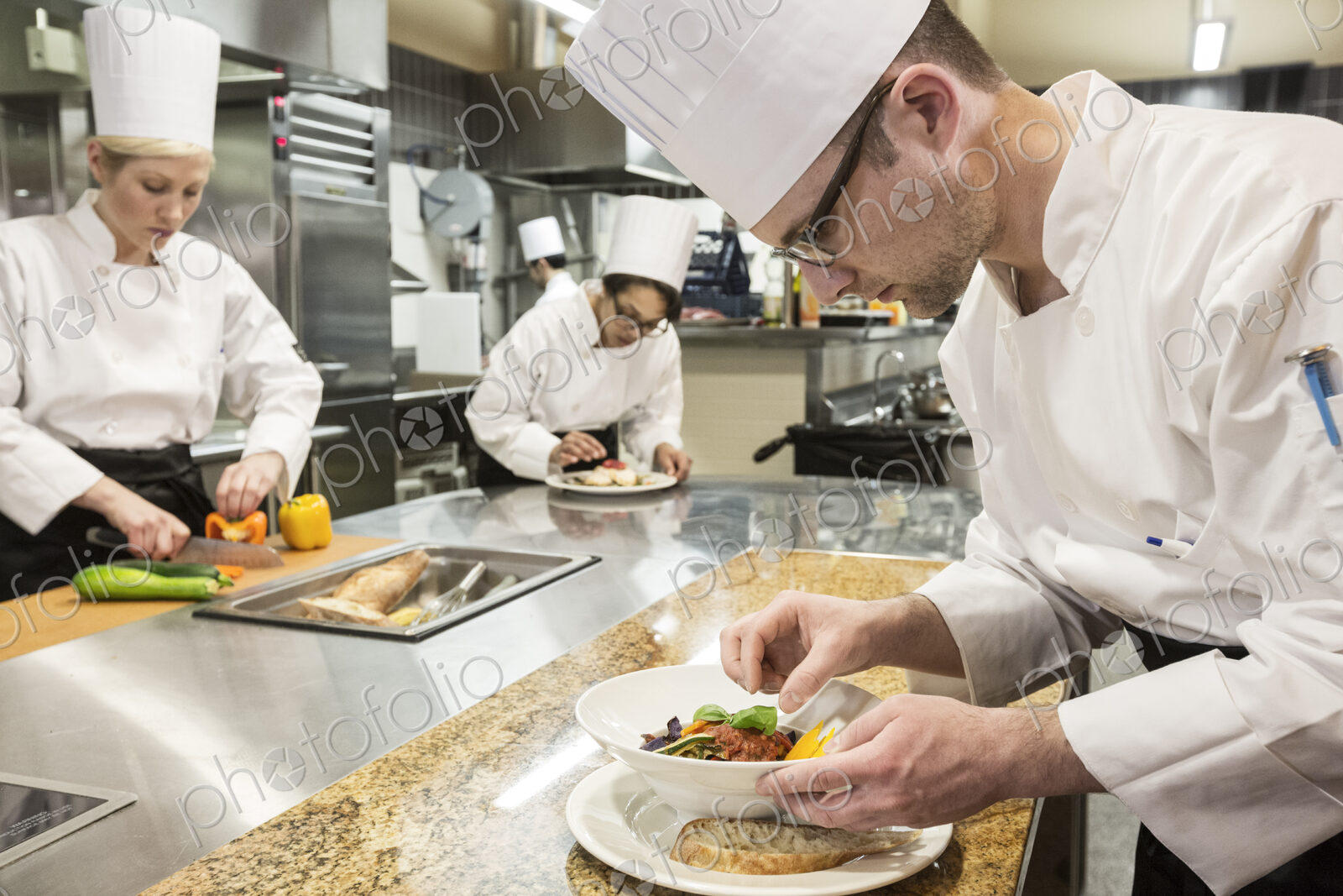 A caucasian male chef putting the finishing touches on a plate of fish in a commercial…