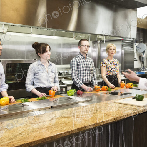 A caucasian male chef teaching a cooking class, multi ethnic group. A caucasian male chef teaching a cooking class, multi ethnic group.