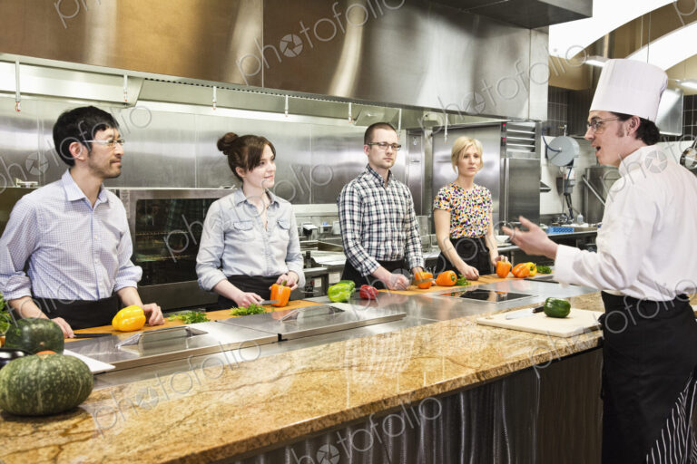 A caucasian male chef teaching a cooking class, multi ethnic group.