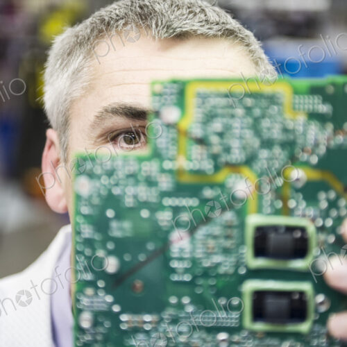 A caucasian male technician examinging a circuit board in a technical research and… A caucasian male technician examinging a circuit board in a technical research and…